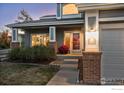 Inviting front entrance with brick columns, red door, and autumn decor at 615 Allen Dr, Longmont, CO 80503