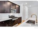 Modern kitchen featuring dark cabinetry, stainless steel appliances, white countertops, and tiled backsplash at 1423 Great Western Dr, Longmont, CO 80501