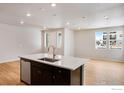 Kitchen island with dark cabinets, light countertops, and stainless steel dishwasher in an open floor plan at 1423 Great Western Dr, Longmont, CO 80501