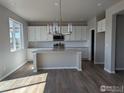 Open kitchen with modern white cabinets, light countertops, and hardwood floors in a spacious layout at 16815 Mckay Dr, Mead, CO 80542