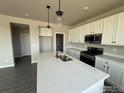 Modern kitchen with white cabinetry, stainless steel appliances, and a large island with a sink at 16835 Mckay Dr, Mead, CO 80542