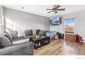 Cozy living room with wood-look floors, a gray sectional sofa, and a ceiling fan at 177 Westin Ave, Brighton, CO 80603