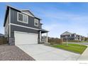 Two-story home with a two-car garage, neutral gray siding and a concrete driveway at 1813 Pinnacle Ave, Lochbuie, CO 80603