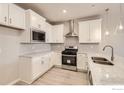 Well-equipped kitchen featuring white cabinetry, stainless steel appliances, quartz countertops, and stylish pendant lights at 2752 Bear Springs Cir, Longmont, CO 80503
