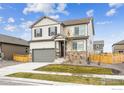 New two-story home featuring stone accents, neutral siding, two car garage, and a well-manicured lawn at 837 Ledge St, Lochbuie, CO 80603
