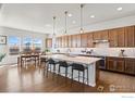 Modern kitchen with an island, stylish pendant lighting, stainless steel appliances, and wood floors at 979 Stagecoach Dr, Lafayette, CO 80026