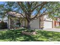Well-kept front yard with lush lawn, mature tree, and charming home exterior with an attached garage at 104 Plowshare Ln, Platteville, CO 80651