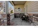 Inviting front porch with stone accents, decorative columns, and seating area at 1108 Wilshire Dr, Berthoud, CO 80513
