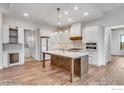 Bright, open kitchen features hardwood floors, white cabinets, and large wood island at 1233 Eliza Ave, Berthoud, CO 80513