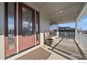 A spacious covered front porch features ample seating and a decorative rug at the entry at 4565 Colorado River Dr, Firestone, CO 80504