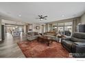 Open-concept living room with fireplace, ceiling fan, and access to the kitchen and patio at 4565 Colorado River Dr, Firestone, CO 80504