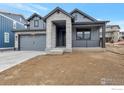 Gray two-story home featuring stone accents, a covered porch, and an attached two-car garage at 461 Muirfield Cir, Louisville, CO 80027