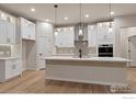 Modern kitchen features white cabinets, stainless steel appliances, pendant lighting, and a large center island at 461 Muirfield Cir, Louisville, CO 80027