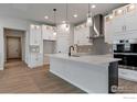 Modern kitchen features white cabinets, stainless steel appliances, pendant lighting, and a large center island at 461 Muirfield Cir, Louisville, CO 80027
