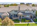 Aerial view of a home with stone accents, a well-manicured lawn, and a charming outdoor seating area at 8887 Tappy Toorie Cir, Highlands Ranch, CO 80129