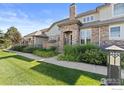 A beautiful two-story home featuring a stone archway, professional landscaping, and a lush green lawn at 8887 Tappy Toorie Cir, Highlands Ranch, CO 80129