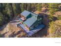 Green mountain home featuring large wraparound deck surrounded by beautiful mature trees at 1406 Pika Rd, Boulder, CO 80302