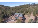 Aerial view of mountain home with wraparound deck and stunning forest landscape at 1406 Pika Rd, Boulder, CO 80302