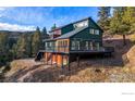 Beautiful green home with a large deck, nestled among the trees on a sloping hill at 1406 Pika Rd, Boulder, CO 80302