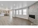 Open-concept living room with fireplace and large windows for natural light, and hardwood floors at 1860 Chaffee Crest Dr, Berthoud, CO 80513
