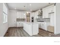 This bright kitchen features white cabinets, stainless steel appliances, a center island, and a mosaic tile backsplash at 1876 Chaffee Crest Dr, Berthoud, CO 80513