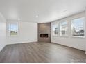 Spacious living room featuring a modern fireplace and a row of bright windows at 1876 Chaffee Crest Dr, Berthoud, CO 80513