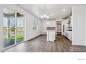Open-concept living and kitchen area with wood flooring, abundant natural light, and sliding glass doors to the backyard at 1876 Chaffee Crest Dr, Berthoud, CO 80513