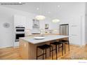 Modern kitchen with a large island, stainless steel appliances, and sleek white cabinets at 2286 Star Hill St, Longmont, CO 80503