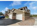 Apartment complex with attached garages, paved parking, manicured landscaping, and neutral exterior colors at 3035 Blue Sky Cir # 10-207, Erie, CO 80516