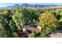 Stunning aerial view of a home nestled among trees with mountain views in the distance at 3660 Larkwood Ct, Boulder, CO 80304