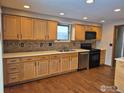 An efficient kitchen with stainless appliances, wood floors, and tile backsplash at 614 Munson Ct, Berthoud, CO 80513