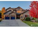 Gorgeous front exterior featuring a stone facade, three-car garage and a well-manicured lawn at 13878 Barbour St, Broomfield, CO 80023