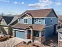 Attractive two-story blue home showcasing a covered front porch, a two-car garage, and meticulous landscaping at 1417 Bluemoon Dr, Longmont, CO 80504