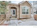 Close-up of front door with stone archway, wreath, and well-maintained landscaping at 1629 Metropolitan Dr, Longmont, CO 80504