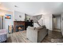 Cozy living room featuring a brick fireplace, wooden floors, and a view of the staircase at 2016 W 101St Ave, Thornton, CO 80260