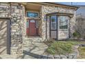 Close up of a stone-covered home with a porch, a red front door, and manicured landscaping at 270 Terra Vista St, Brighton, CO 80601