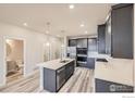 Open kitchen featuring stainless appliances, large island with sink, and adjacent powder room at 2824 South Flat, Longmont, CO 80503