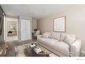 A neutral-toned living room featuring a comfortable sofa, a workspace, and a view of the hallway at 3009 Madison Ave # 317, Boulder, CO 80303