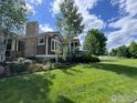 Well-maintained home with lush lawn, mature trees, and stone chimney at 3805 Glenn Eyre Dr, Longmont, CO 80503