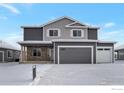 Two story gray home with stone accents, a two car garage, and snow covered front lawn at 5755 Pintail Way, Frederick, CO 80504