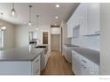 Open kitchen featuring an island, stainless sink and light countertops with all white cabinets at 5755 Pintail Way, Frederick, CO 80504