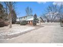 A two-story home with blue siding, a driveway with a basketball hoop, and trees at 7169 Mount Meeker Rd, Longmont, CO 80503