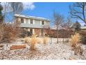 Two-story house with light blue siding and partial snow cover and various bushes and trees at 7169 Mount Meeker Rd, Longmont, CO 80503