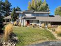 Charming two-story home with a well-manicured lawn, solar panels, and a red front door at 7240 Clubhouse Rd, Boulder, CO 80301