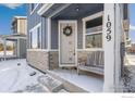 Inviting front porch with a rustic wooden bench and a decorative wreath on the stylish front door at 1059 Spartan Ave, Berthoud, CO 80513