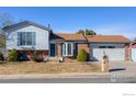 Charming home featuring brick and light blue siding, mature landscaping, and an attached two-car garage at 1135 Fern St, Broomfield, CO 80020