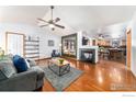 Open-concept living room with a fireplace, hardwood floors, and a view into the adjacent kitchen at 1170 Jefferson Dr, Berthoud, CO 80513