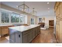 Spacious kitchen featuring a large island with marble countertops, designer lighting, and hardwood floors at 1321 Onyx Cir, Longmont, CO 80504