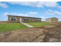 Tan single-story home with green lawn and matching storage shed at 1363 S Edgar Ct, Strasburg, CO 80136