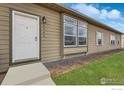 Close up of the front door, showing house numbers, siding, and green lawn at 1363 S Edgar Ct, Strasburg, CO 80136